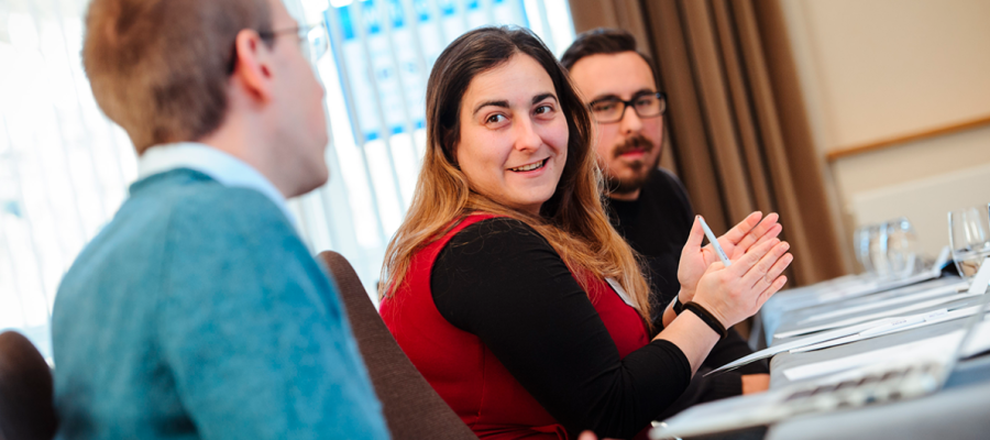 A woman and two men sat around a meeting table