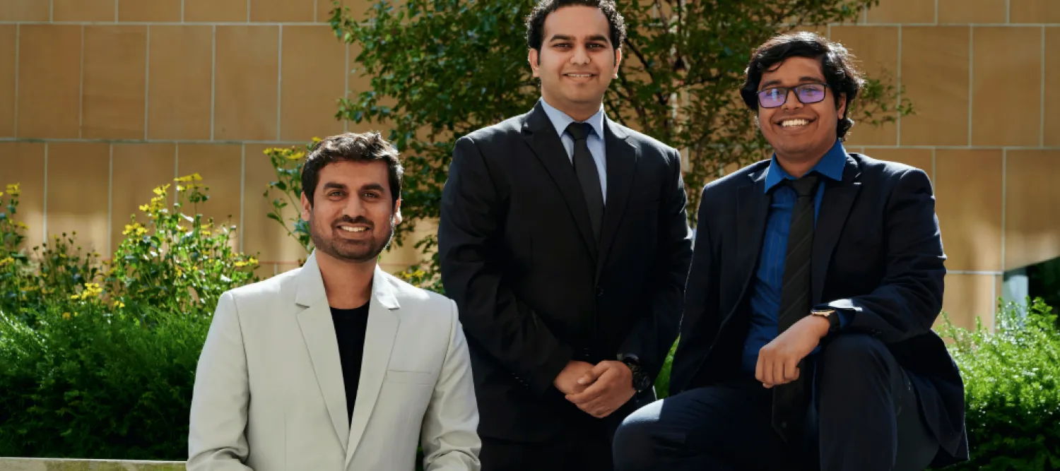 Three men, wearing suits, sat outside on a bench. 