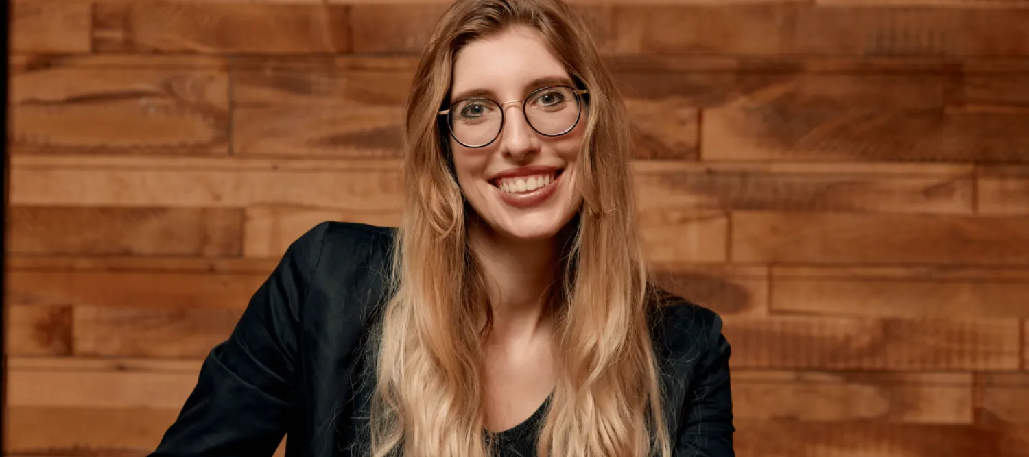 Smiling woman wearing blazer and glasses.  