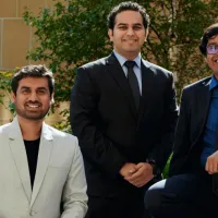 Three men, wearing suits, sat outside on a bench. 