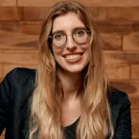 Smiling woman wearing blazer and glasses.  