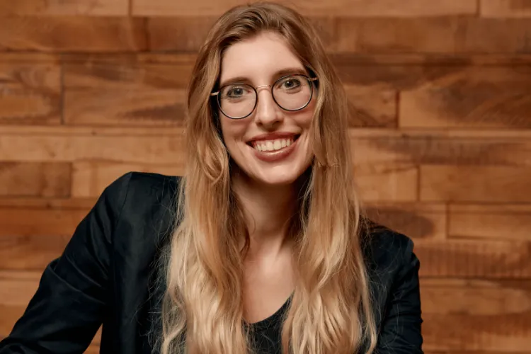 Smiling woman wearing blazer and glasses.  