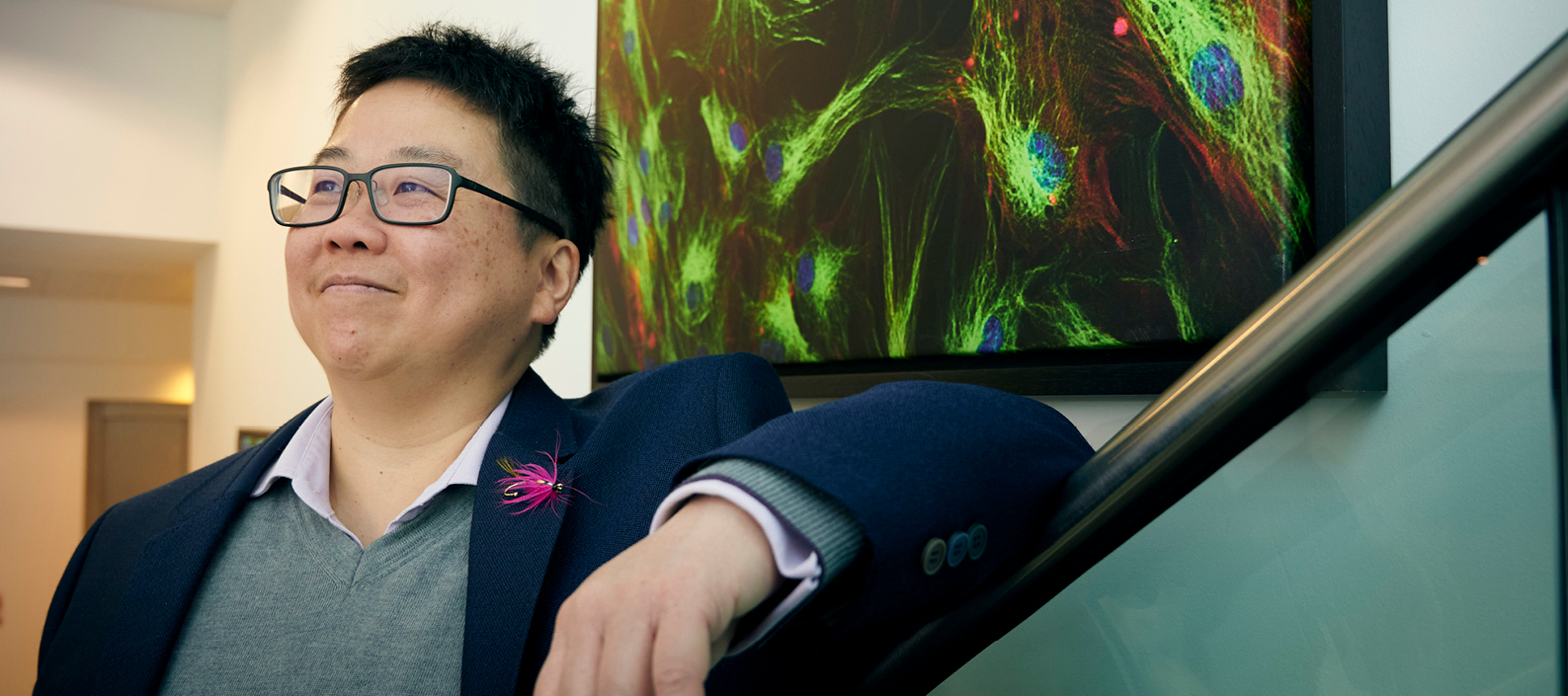 Image of Tsz-Yan Milly Lo leaning against a staircase with an abstract painting behind them