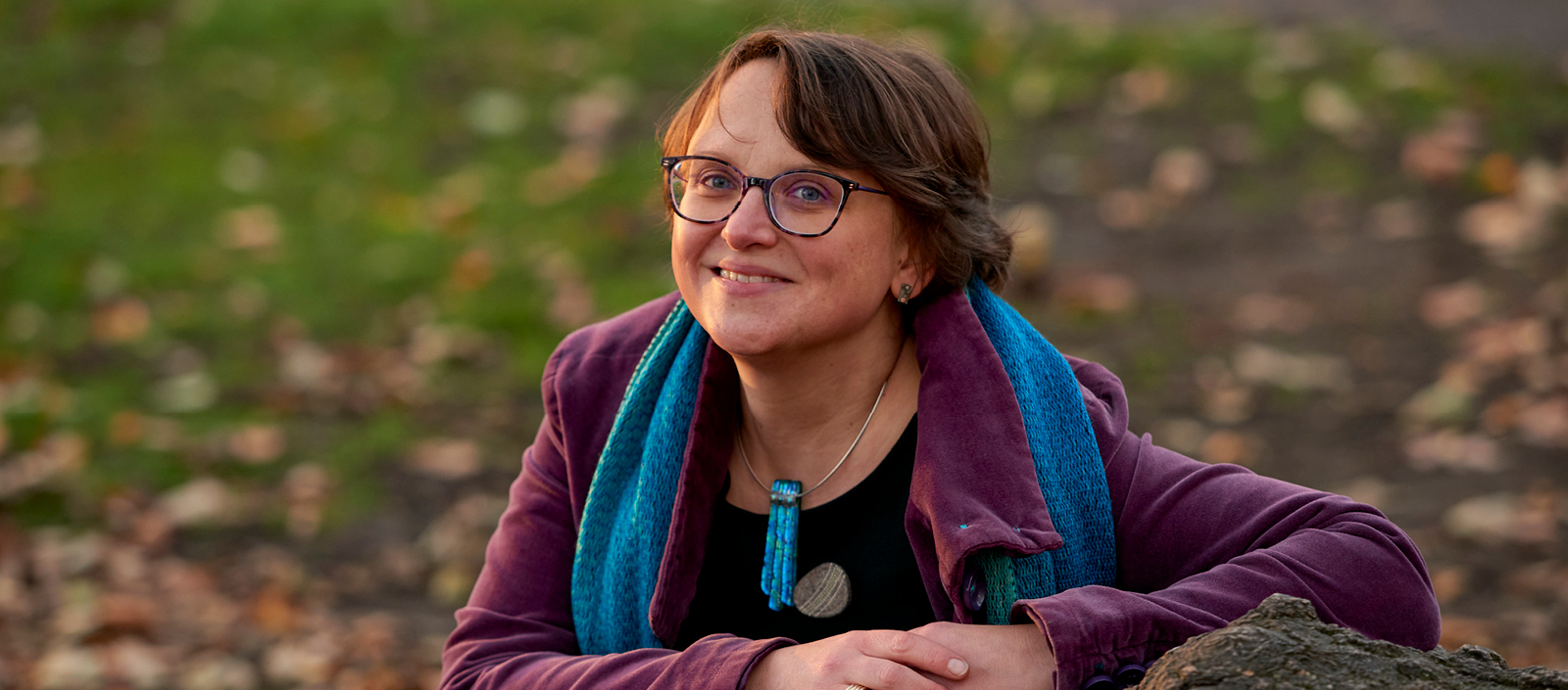 Image of Dr Tanja Romankiewicz leaning on a fallen tree stump