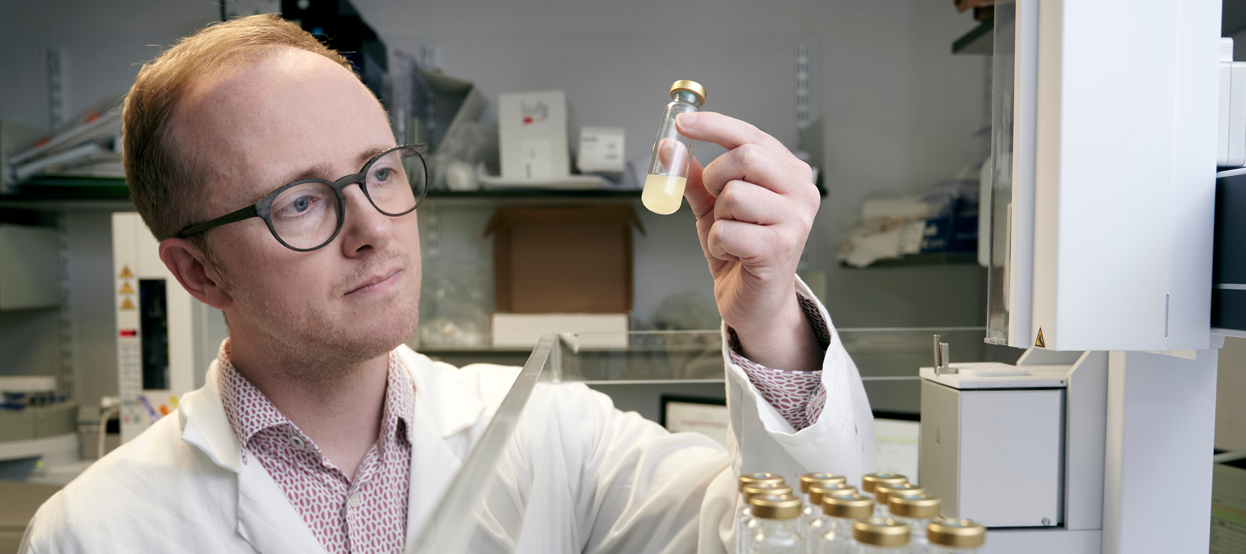 Image of Professor Stephen Wallace in a lab looking at the contents of a test tube